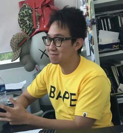 Pek Kim Yew, founder and director, in a yellow T-shirt at his desk